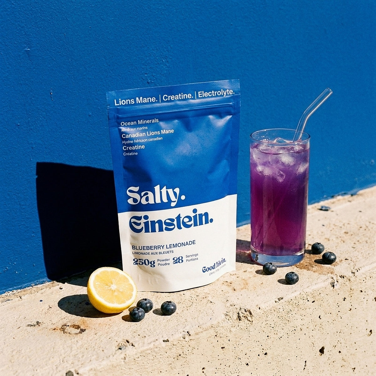 Salty Einstein blueberry lemonade pouch next to a glass of the purple drink on a sunny concrete ledge